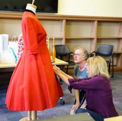 Julia and Pam kneeling in front of a dress on a dress form