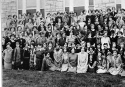 Group photo of female students with a variety of hairstyles in front of bluestone building