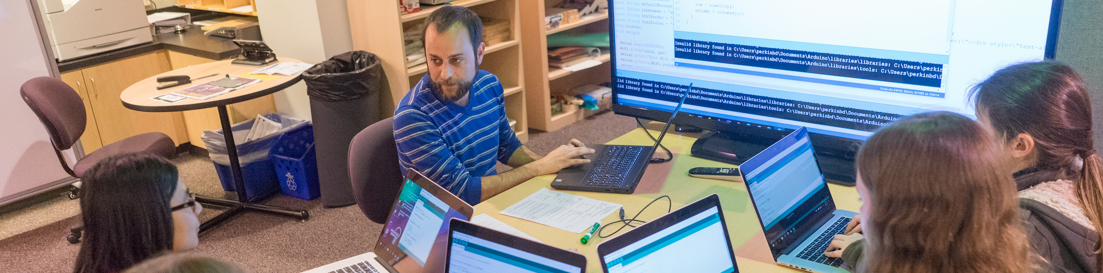 Photo of Libraries staff helping four faculty with laptops and large screen