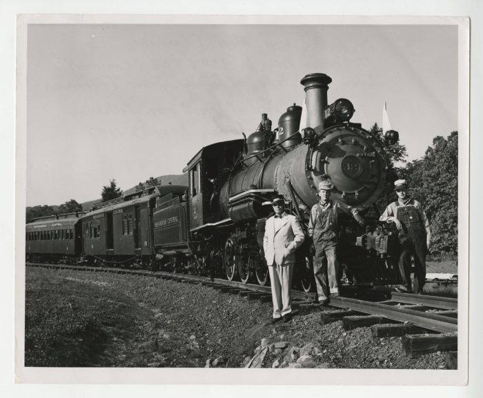 Dr. Paul S. Hill, C. Grattan Price Jr., and Wade W. Menefee Jr. standing beside the Tweetsie locomotive on the day of the Golden Spike Ceremony, 1953 May 29.